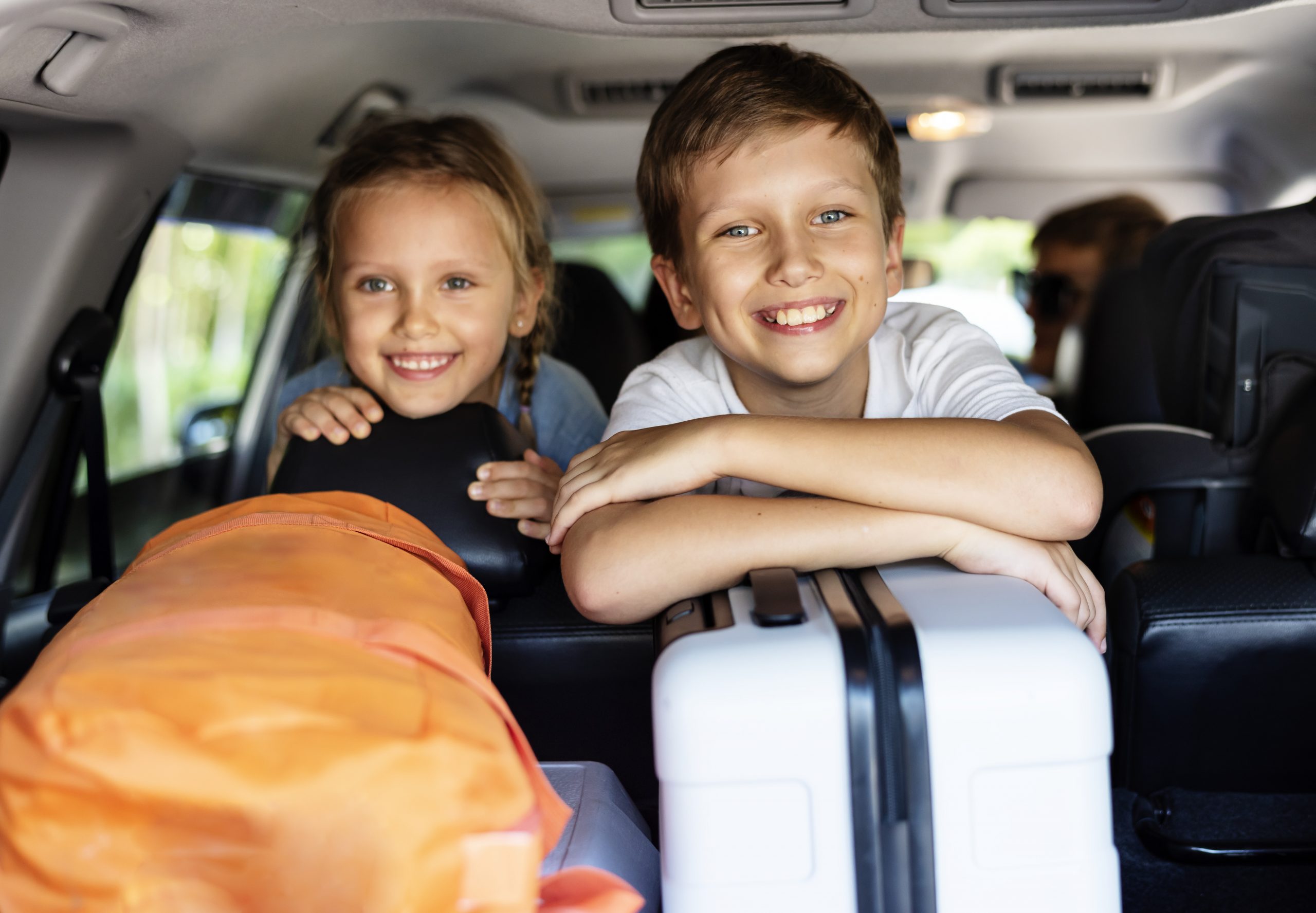 Bilde av to barn som sitter i en bil og skal på ferie